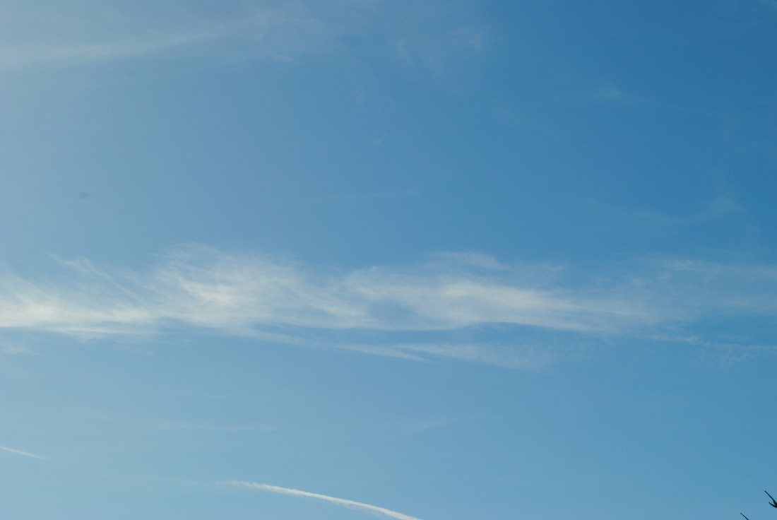 A thin cloud crossing a broad blue sky