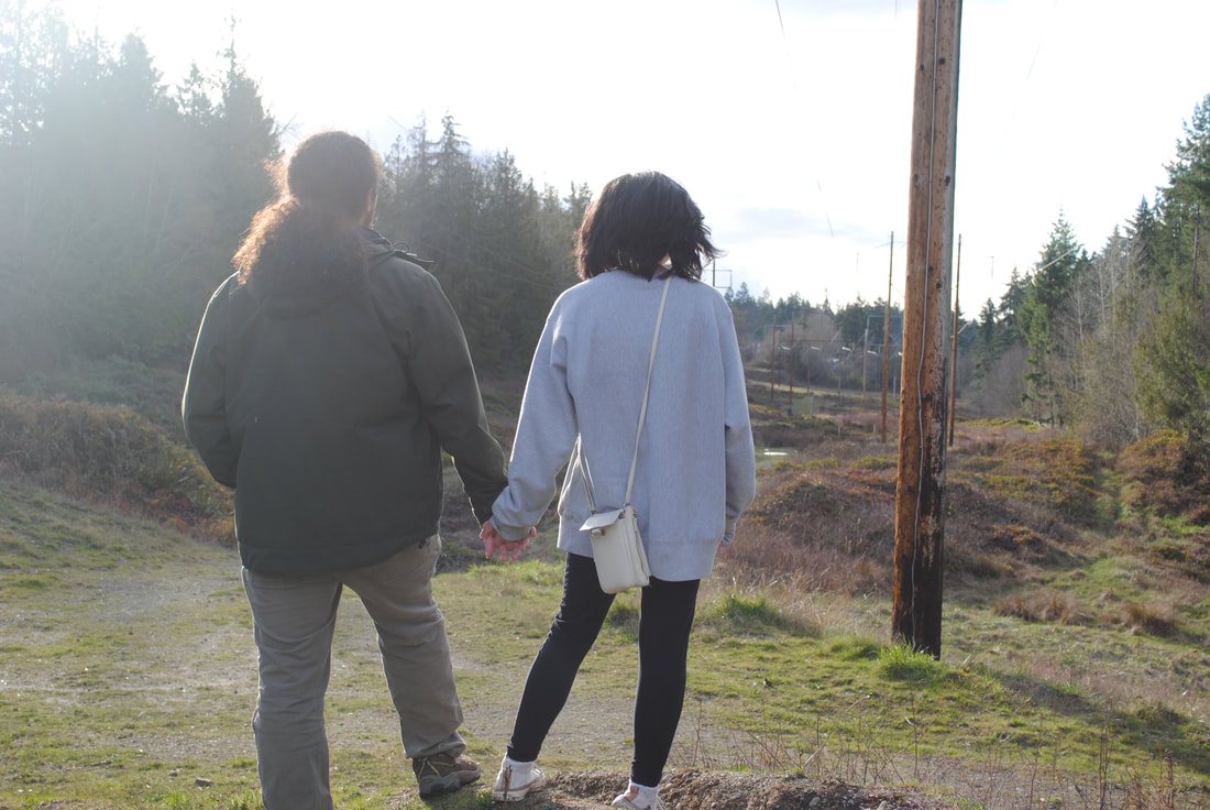 Two people walking side by side down a path through a powerline clearing
